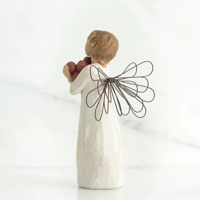 Decorative angel figurine holding two apples on a white background