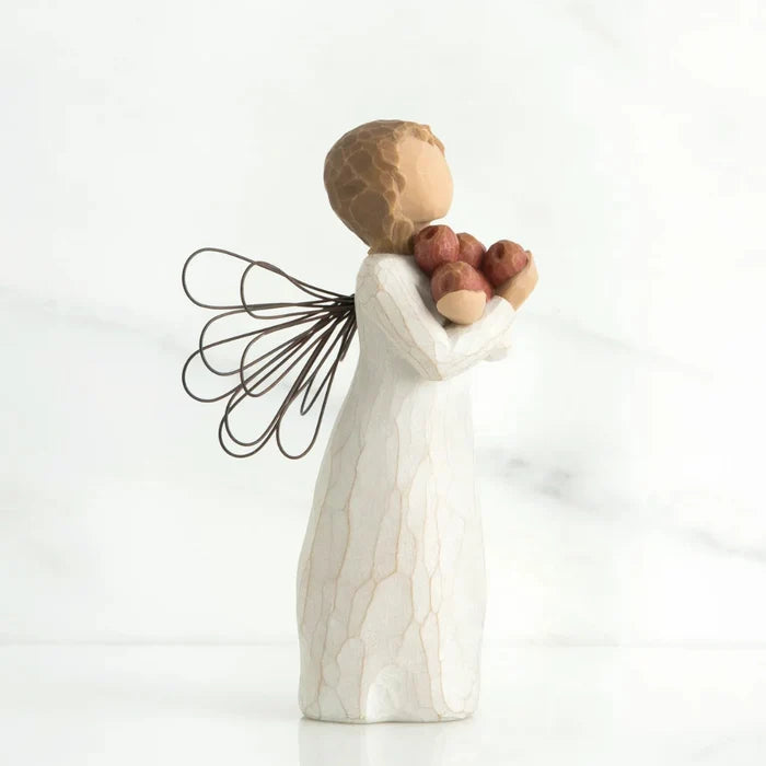 Decorative angel figurine holding apples against a white background
