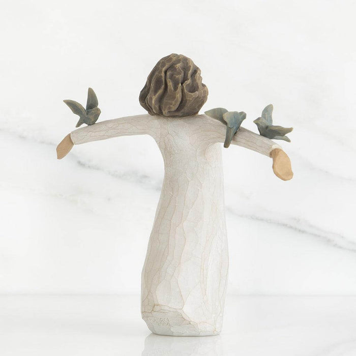 Ceramic angel figurine with outstretched arms and three birds on a white background