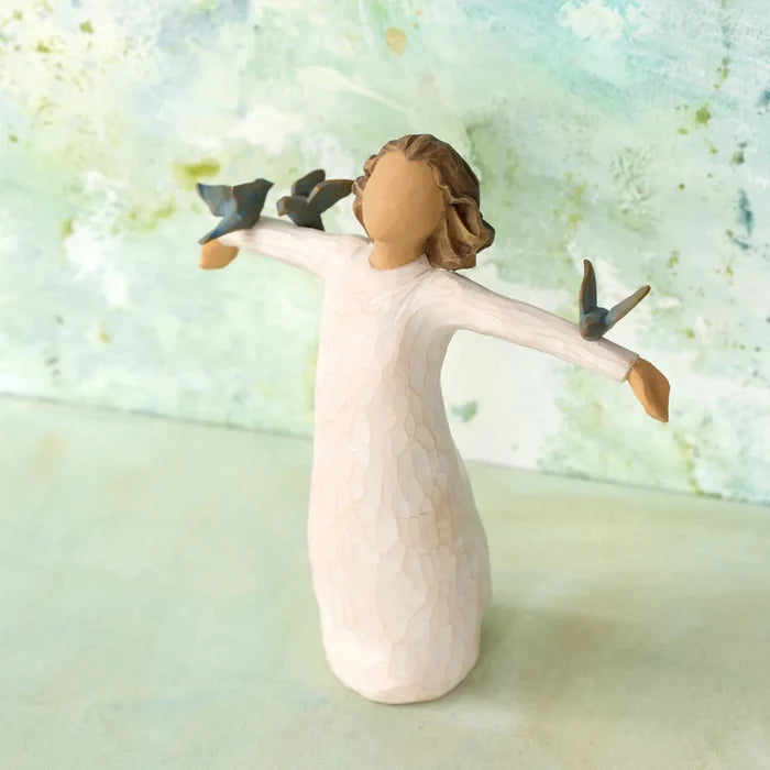 Decorative figurine of a woman with birds on her hands against a light, abstract background