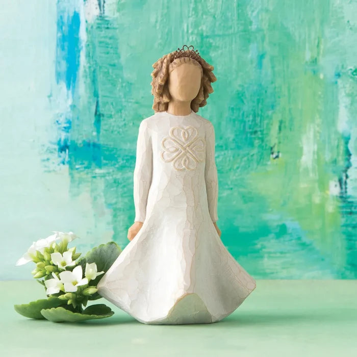 Decorative figurine of a woman in a white dress with a floral design, standing next to a small plant against a watercolor background.