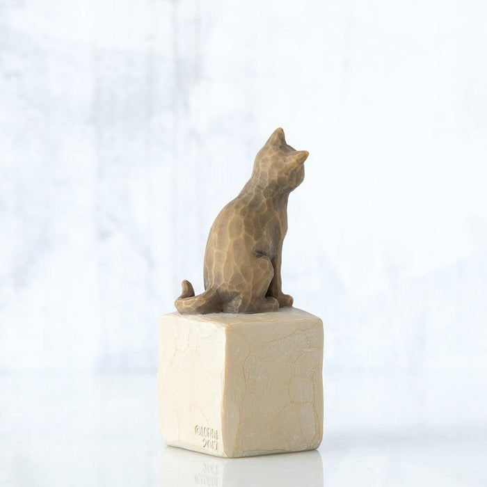 Stone sculpture of a cat on a white block with a white background