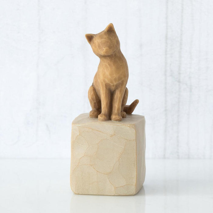 cat figurine on a stone base against a white background