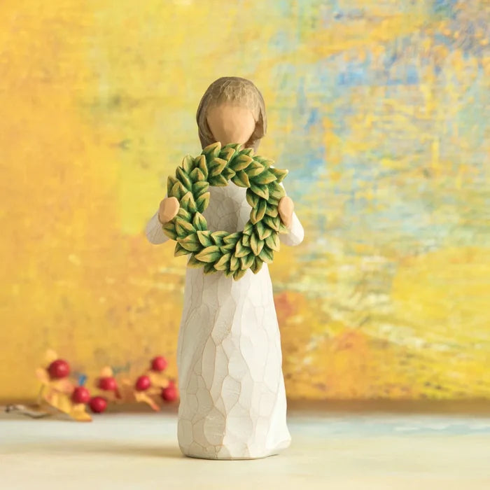 Decorative figurine of a woman holding a green wreath against a blurred autumn background.