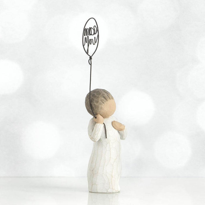 Decorative angel figurine holding a heart-shaped balloon with 'miss you' on a white background