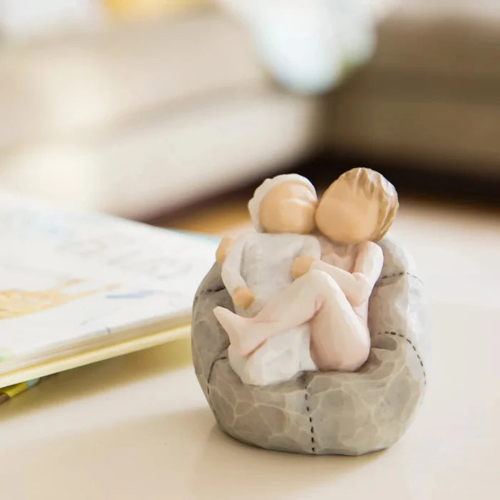 Small figurine of two people sitting together on a rock with a blurred background