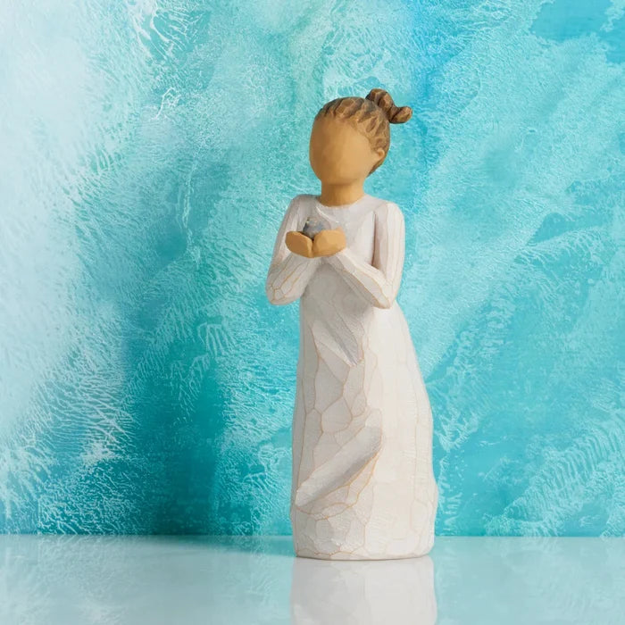 This hand-painted sculpture reflects the quiet acts of kindness and nurturing that help others grow and thrive. Woman holding a baby bird on a light blue background
