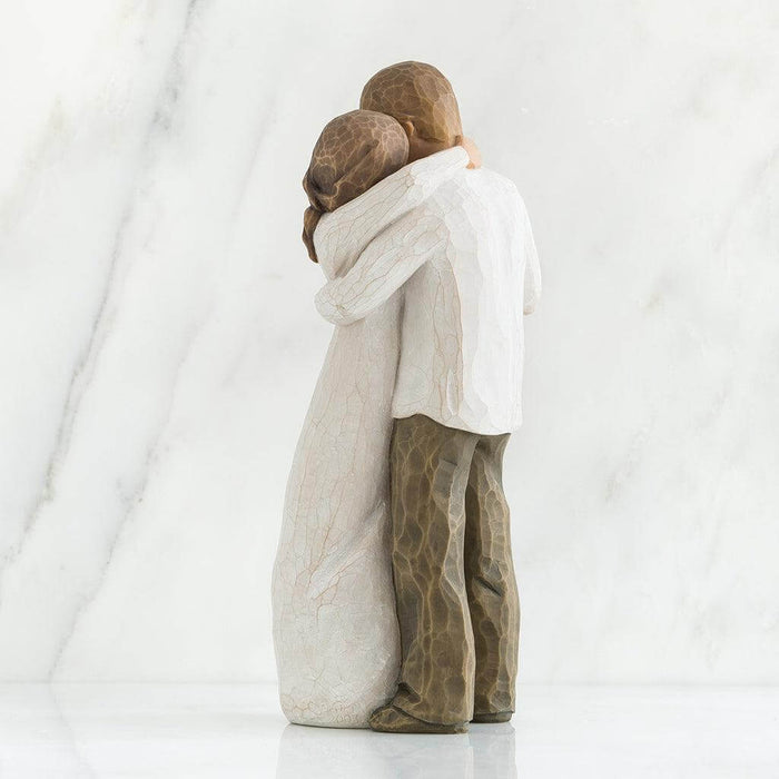 Two stone sculptures of a couple embracing on a white background