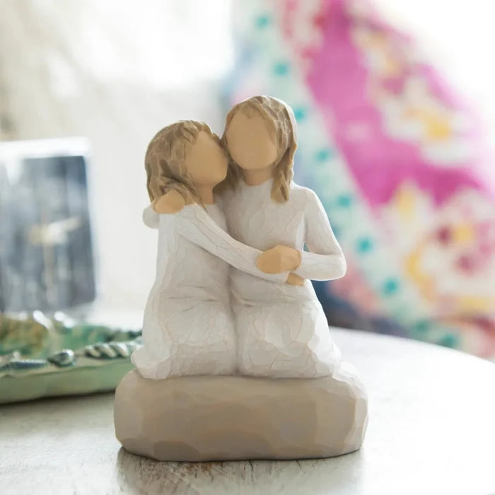 Willow Tree Sister Mine figurine showing two sisters sitting together on a table with a pinkish background