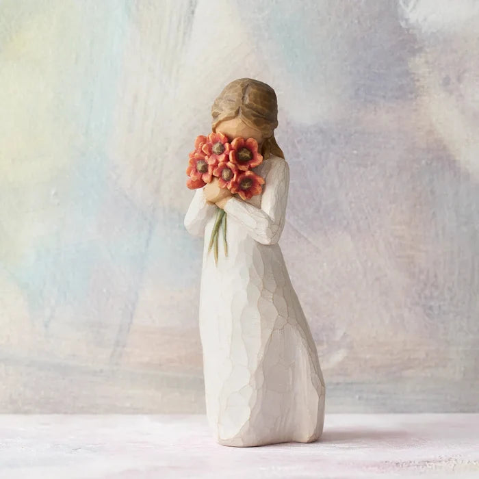 Statue of a woman holding flowers against a soft, multicolored background