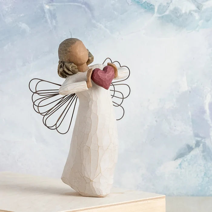 Angel figurine holding a heart against a light blue background