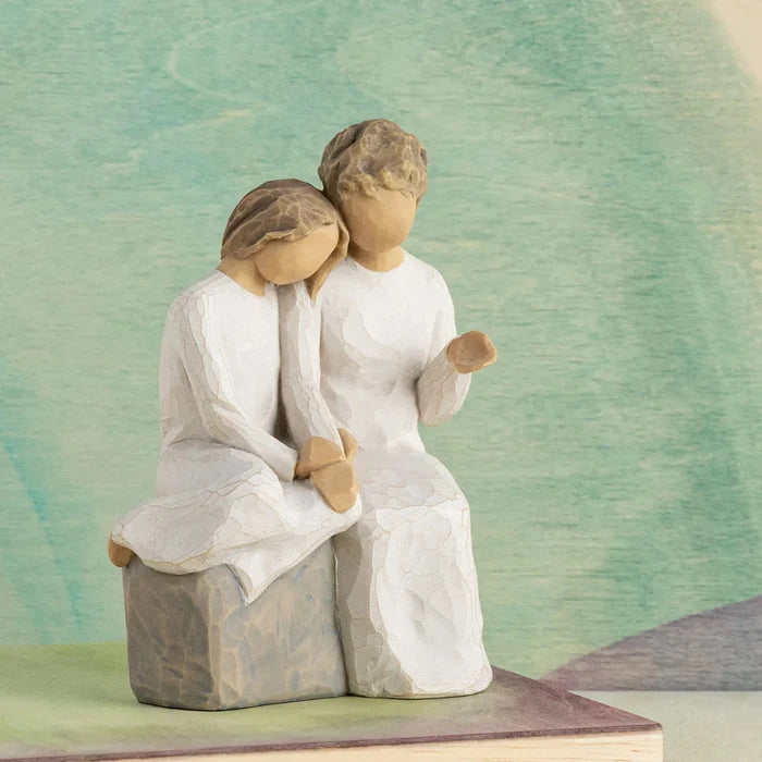 Statue of grandmother and granddaughter sitting together on a textured surface with a soft, blurred background