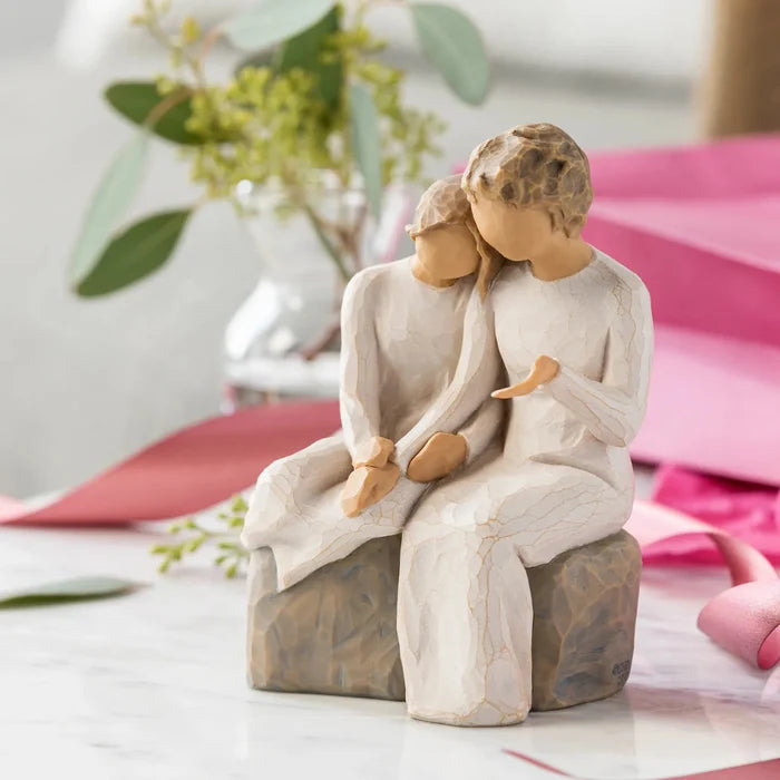 Statue of grandmother and granddaughter  embracing on a rock with a blurred background