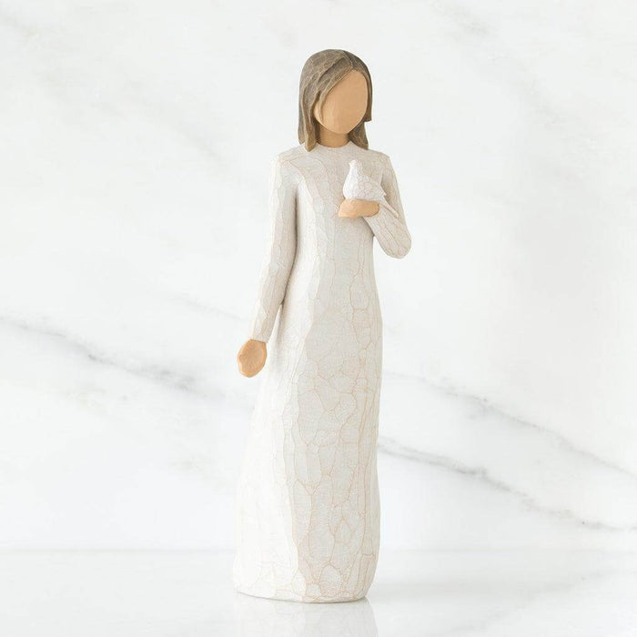Figurine of a woman in a long, light-colored dress holding a dove against a white background