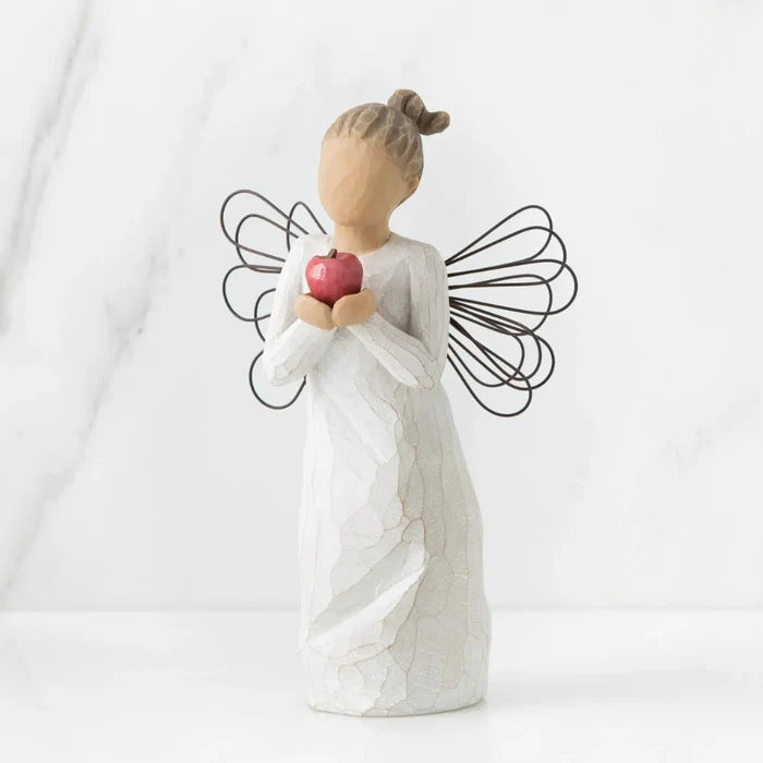 White angel figurine holding a red heart against a white background