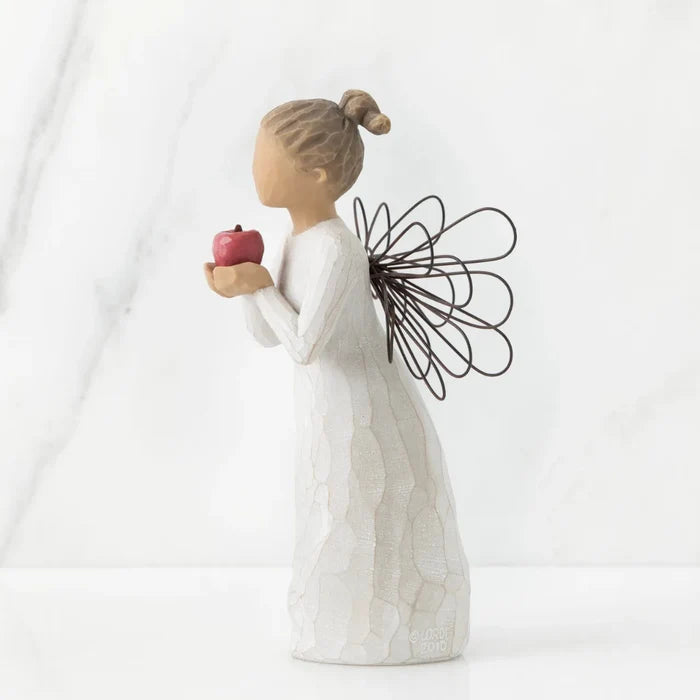 Decorative figurine of a woman holding an apple against a white background